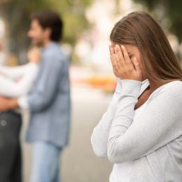 Upset woman crying, seeing her boyfriend with other girl in park
