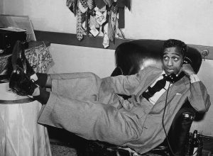Sammy Davis Jr. photographed lounging in a chair, holding a phone circa 1955