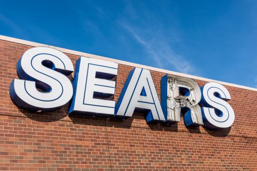 A closeup of a Sears exterior sign with the R letter broken