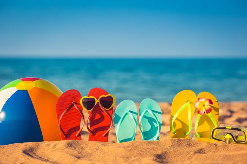 flip flops, sunglasses, and beach ball on the sand.