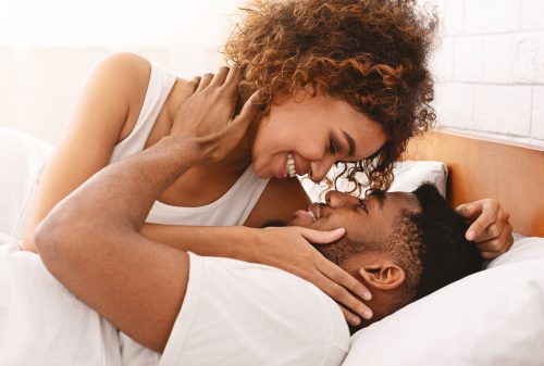 Man and woman holding each other's faces in bed 