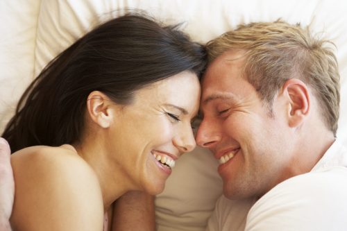 Man and woman laughing in bed