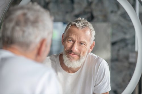 Mature bearded man looking into mirror