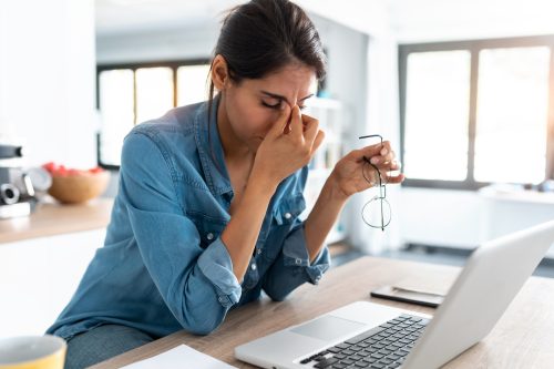 woman looking stressed in front of her laptop at work