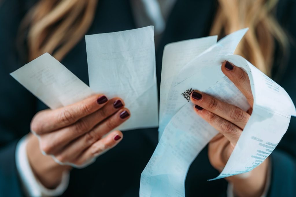 close up on woman's hands holding several receipts