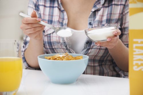 Woman Spooning Sugar onto Cereal