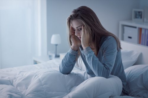 Woman in her bed struggling with anxious thoughts.