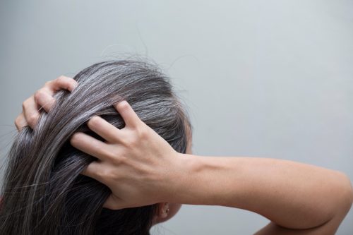 A woman pulling her gray hair back.