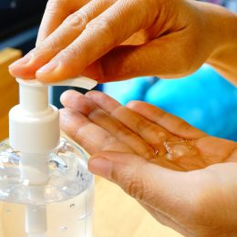 A close up of a person putting gel hand sanitizer into their palm with a pump bottle