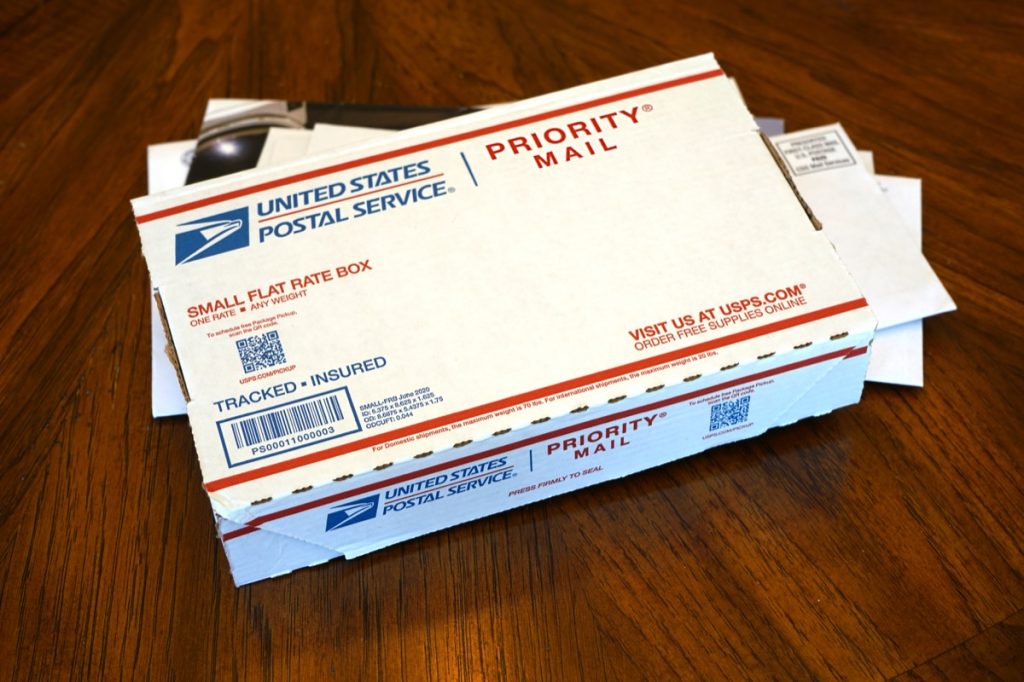 USPS Priority Mail package on a stack of the daily mail.