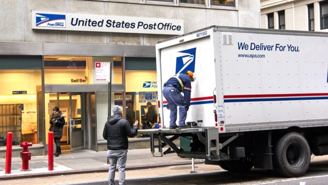 NEW YORK, USA - DECEMBER 14, 2018: USPS postman on a mail delivery truck in New York. USPS is an independent agenc of US federal government responsible for providing postal service in the US.