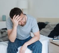 Restless man waking up early with headache after rough night