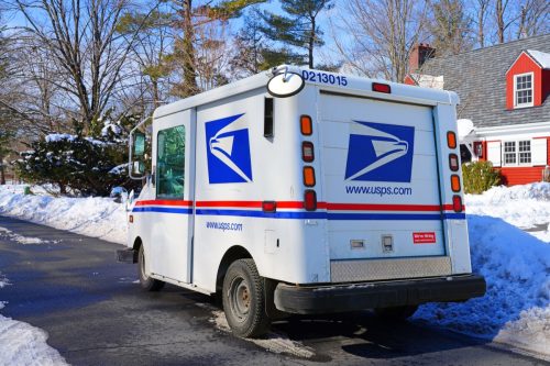 Winter view of a delivery truck from the United States Postal Service (USPS) on the street in New Jersey, United States after a snowfall.