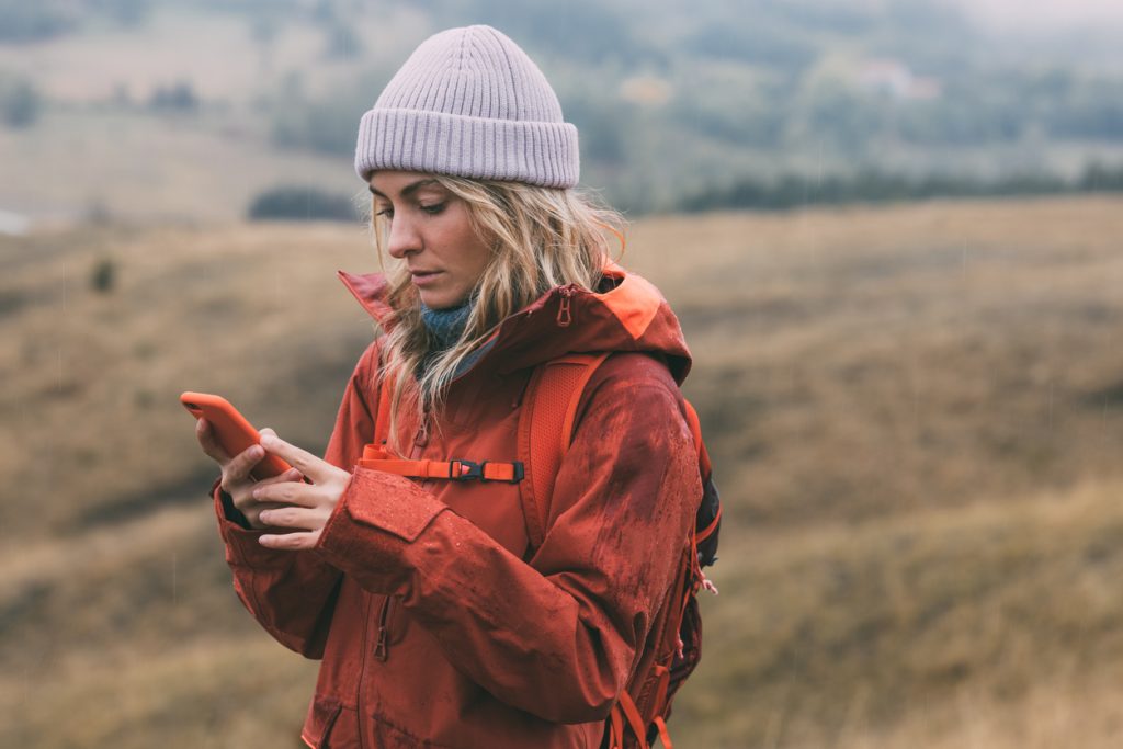 A young woman using her iPhone while outdoors on a hike
