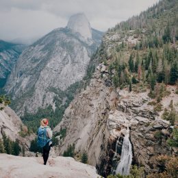 A hiker standing on a peak overlooking Yosemite National Park