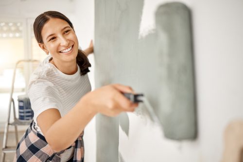 Cận cảnh một phụ nữ trẻ lăn sơn xanh xám lên tường.
