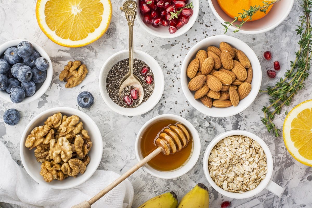 Ingredients for a healthy breakfast, nuts, oatmeal, honey, berries, fruits, blueberry, orange, pomegranate seeds, almonds, walnuts. The concept of natural organic food in season. Top view