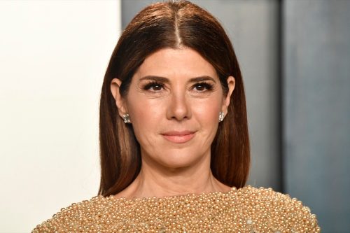 Marisa Tomei at a red carpet event wearing a gold dress. 