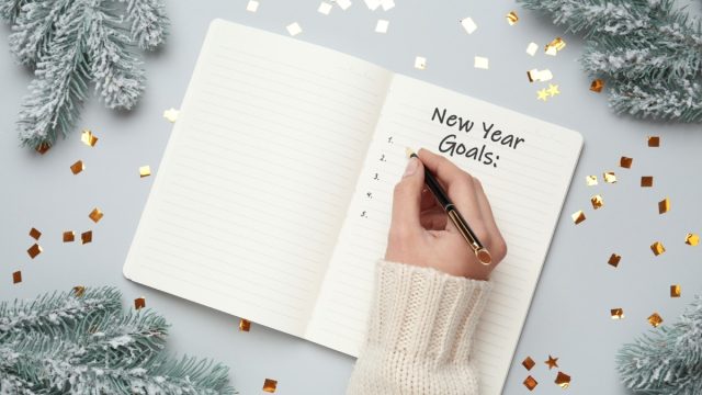 Woman's hand writing down new years goals or resolutions