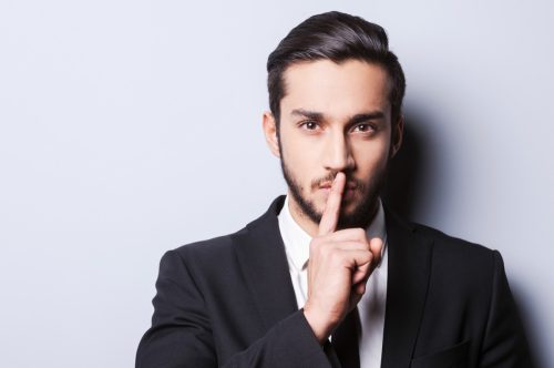Man with his finger on his mouth, having a secret.