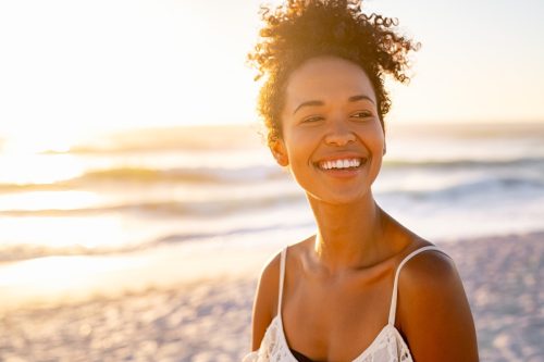 Woman smiling by the ocean at sunset. 
