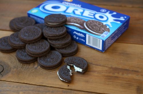 Loose Oreos and a cookie box sitting on a wood table.