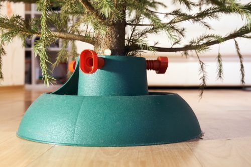 Close up of a green plastic Christmas tree stand with red screws.