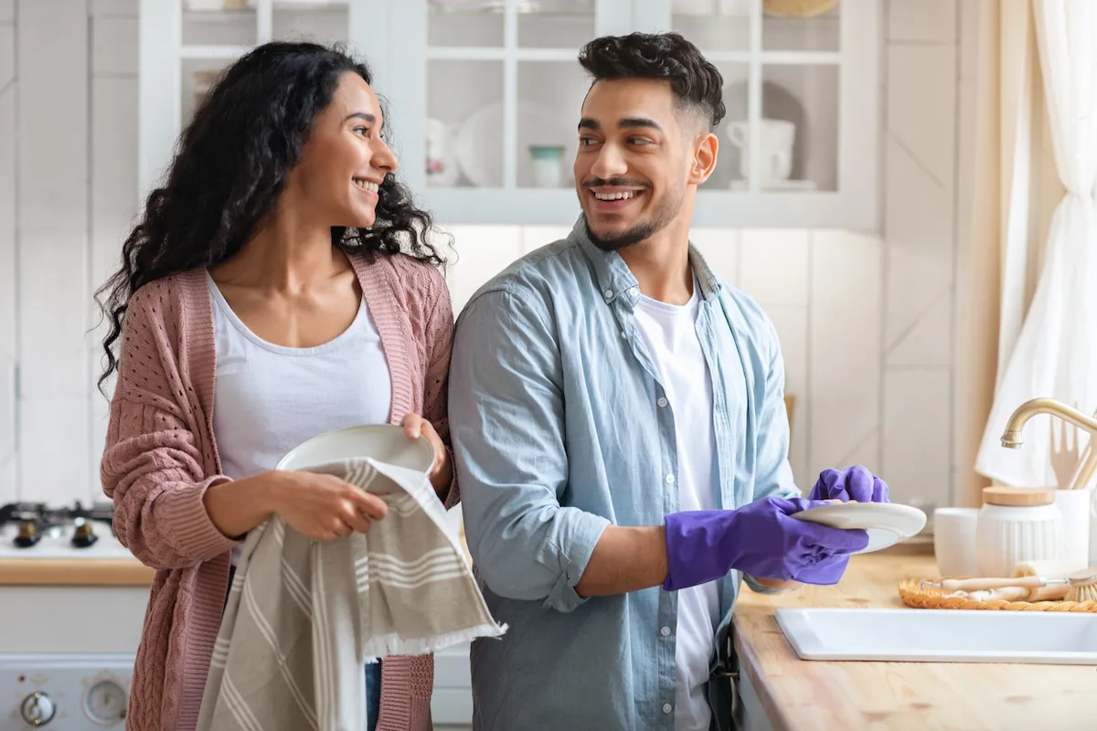 A smiling young couple doing the dishes together.