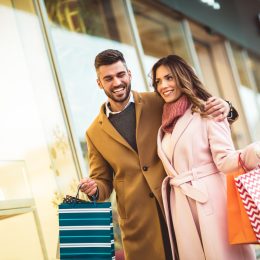 A hetero couple walking down the street with shopping bags