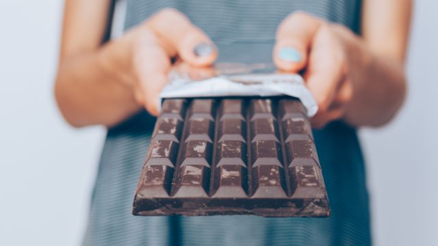 Close up of a person's hands holding a large bar of dark chocolate