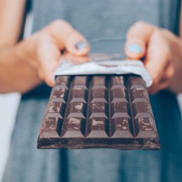 Close up of a person's hands holding a large bar of dark chocolate
