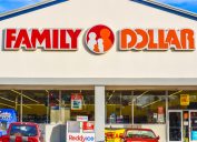 Horizontal, medium closeup of "Family Dollar" chain discount store's exterior facade brand and logo signage in red and orange letters above glass store front.