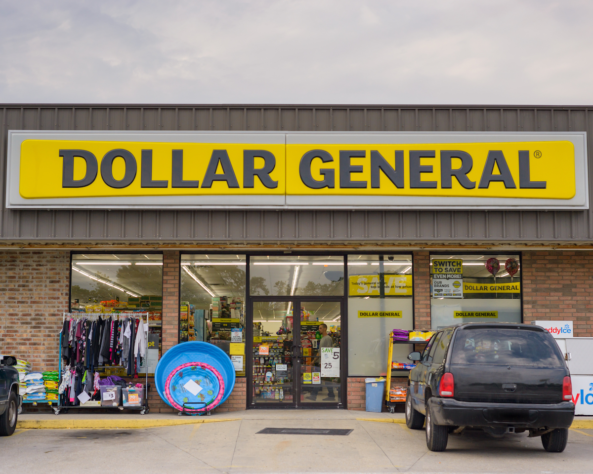 The front of a Dollar General store with a black SUV parked in front.
