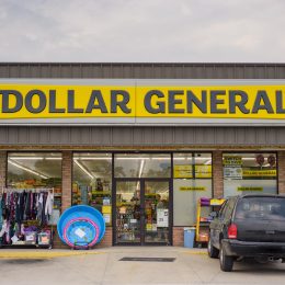 The front of a Dollar General store with a black SUV parked in front.