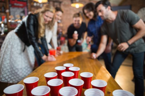 group of friends playing beer pong at a party