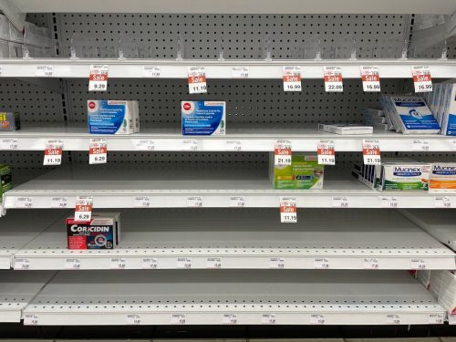 Empty shelves in a pharmacy due to supply shortages of cold, cough, and flu medication and increased demand due to seasonal illnesses
