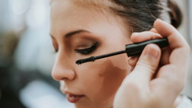 Makeup artist applying mascara onto the model