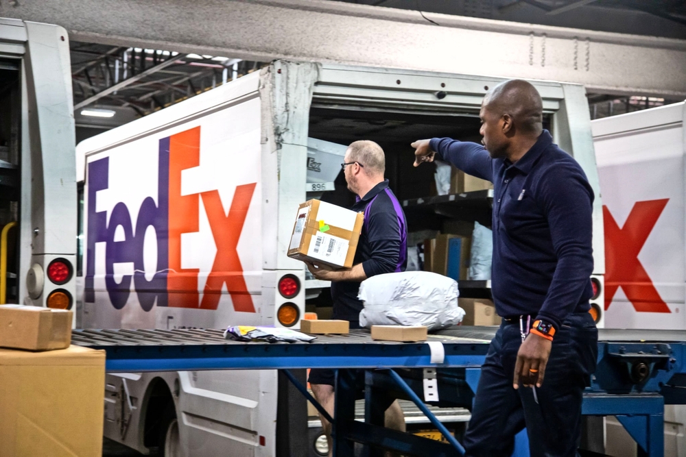 Two FedEx employees sorting packages onto a truck