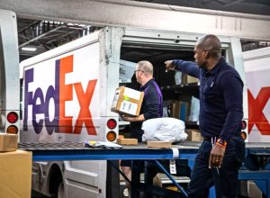 Two FedEx employees sorting packages onto a truck