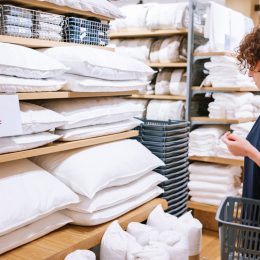 woman enjoying her shopping in the department store, she is looking for pillows and sheet.