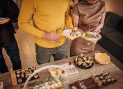 Close up of young people sampling appetizers at a holiday party.