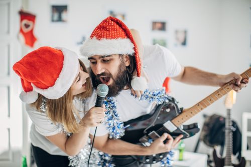 young man and woman singing in santa hats togehter