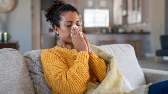 Woman with a cold blowing her nose.