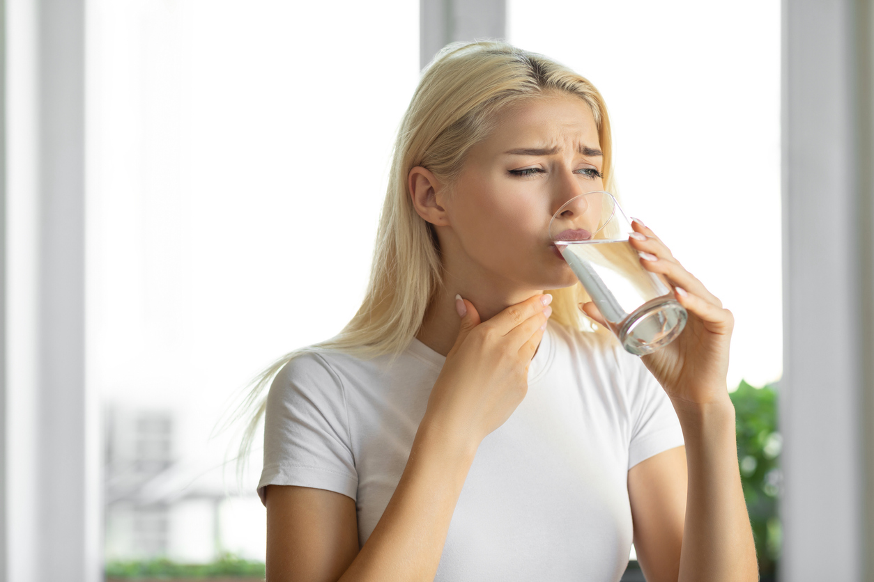 Woman drinking water and having trouble swallowing. 