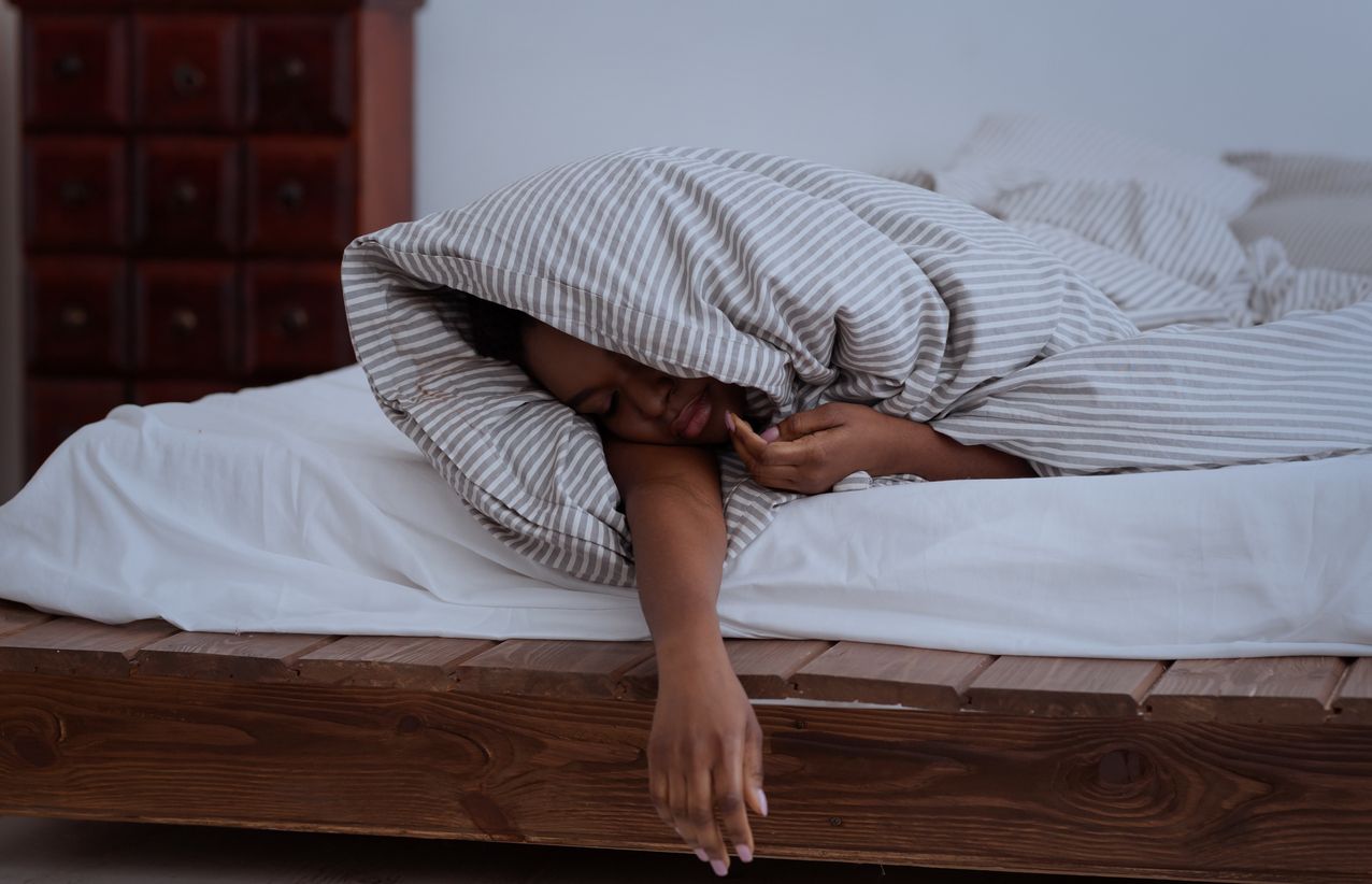 Person sleeping with a pillow over their head.