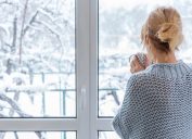 Woman looking out a window at the snow.