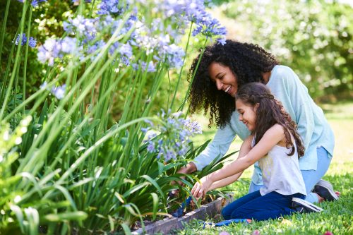 Smiling mother and daughter doing gardening outdoors in spring