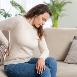 Woman sitting on a couch suffering from back pain.