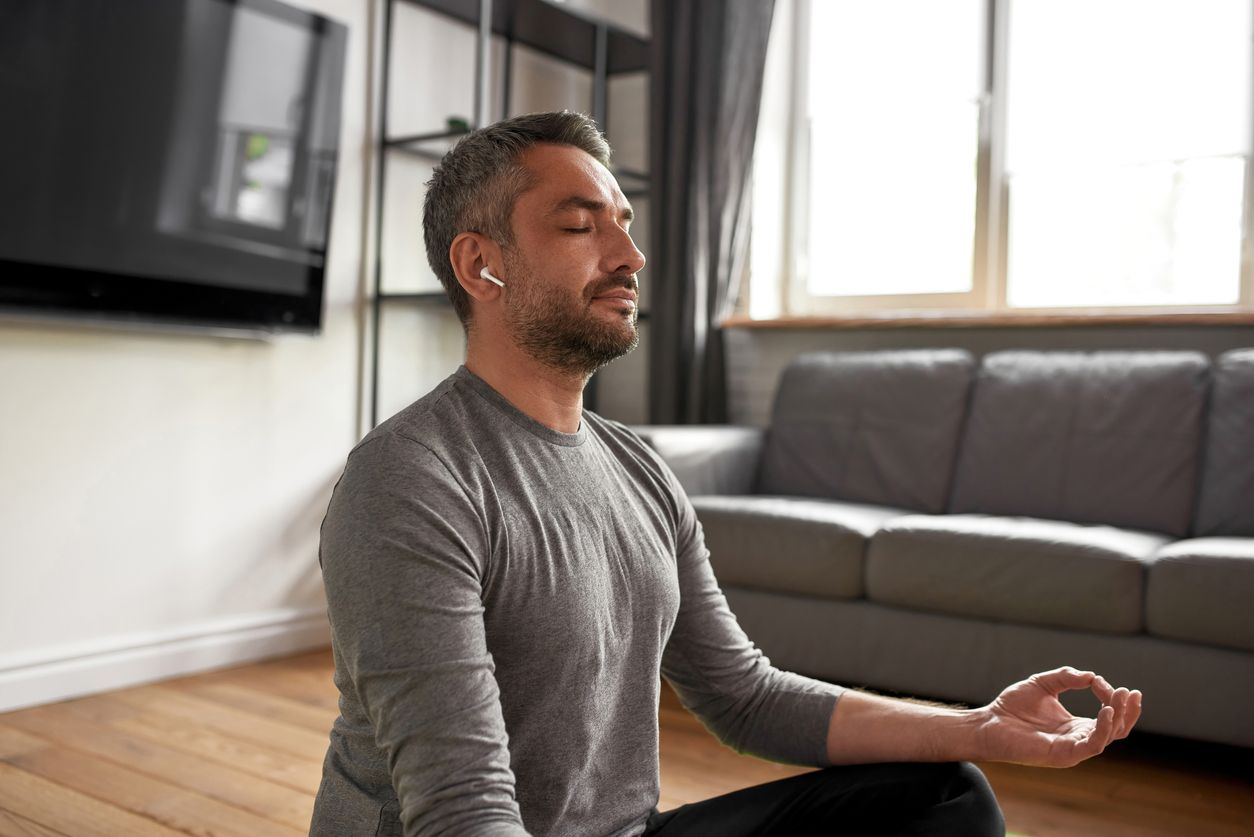 Man meditating in living room.