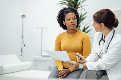 Doctor holding paper document while talking to a patient.